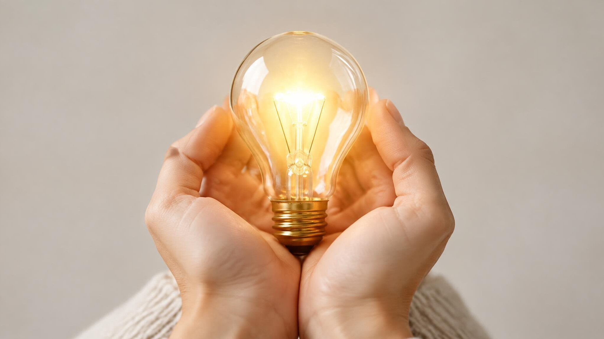 Hands holding a glowing lightbulb symbolizing new ideas and understanding