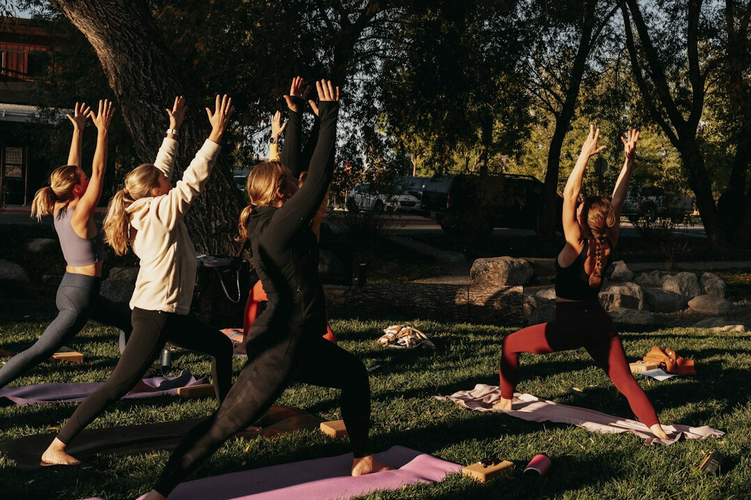 Group of people stretching and exercising together outdoors during a wellness workshop