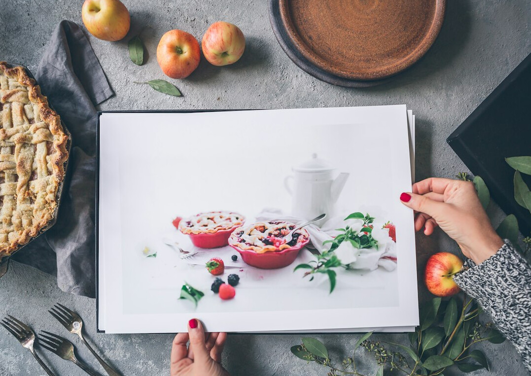 Person writing a healthy meal plan in a notebook surrounded by fresh fruit